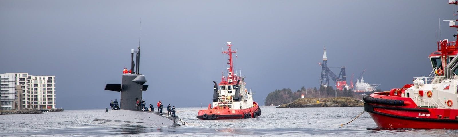 Submarine escorted by tugboats in the water