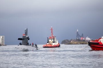 Submarine escorted by tugboats in the water