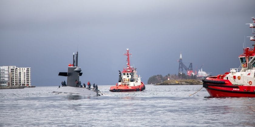 Submarine escorted by tugboats in the water